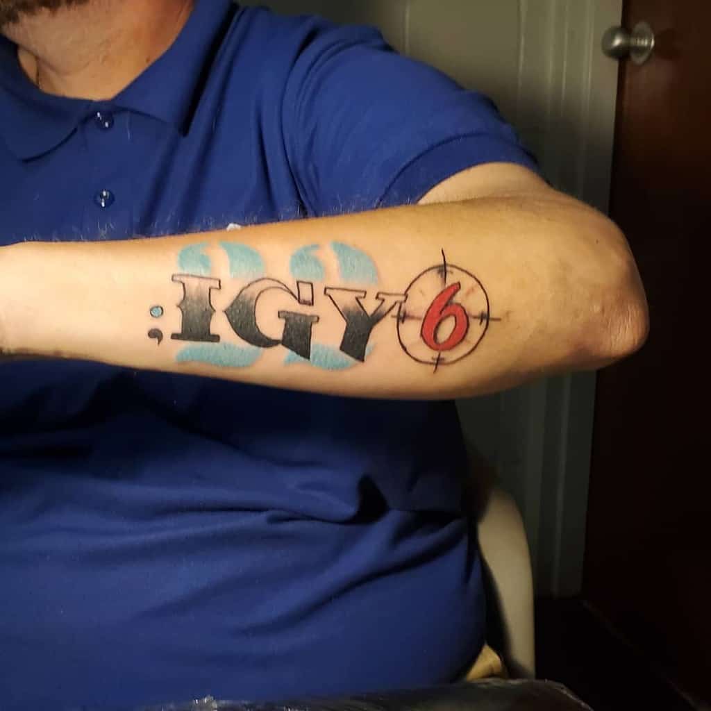 Man with a forearm tattoo reading "; IGY6" in black and red