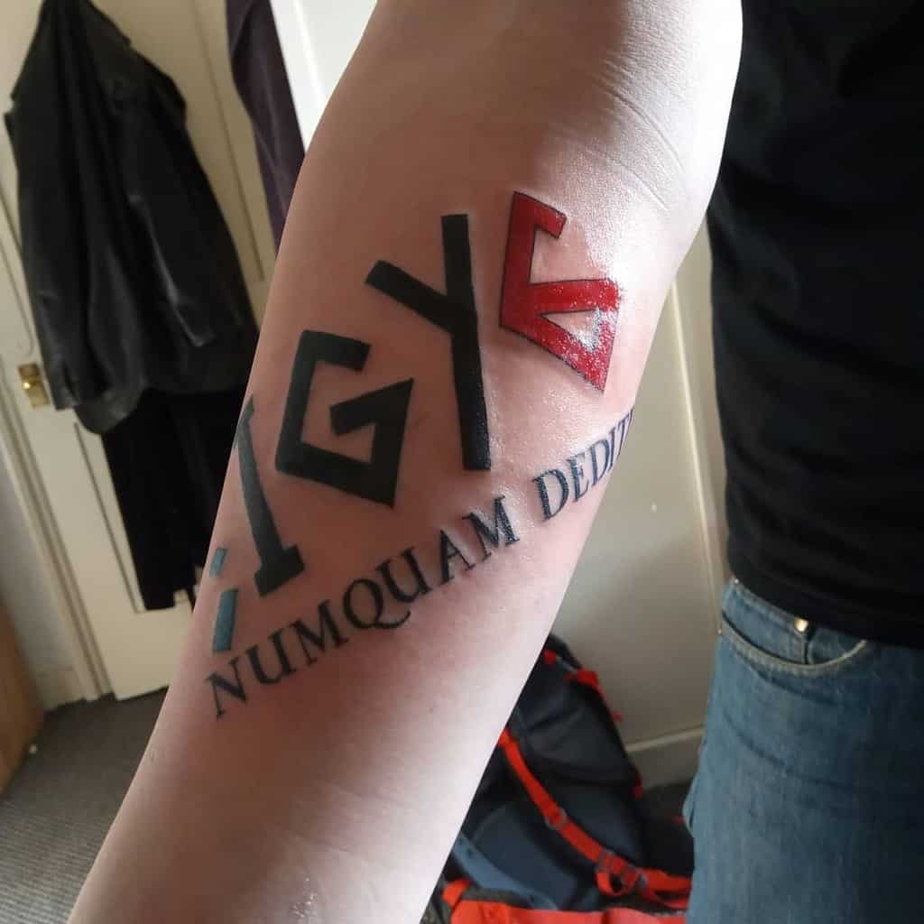 Forearm tattoo with 'IGY6' in bold letters, a red 6, and the Latin phrase 'Numquam Deditio' below, symbolizing resilience