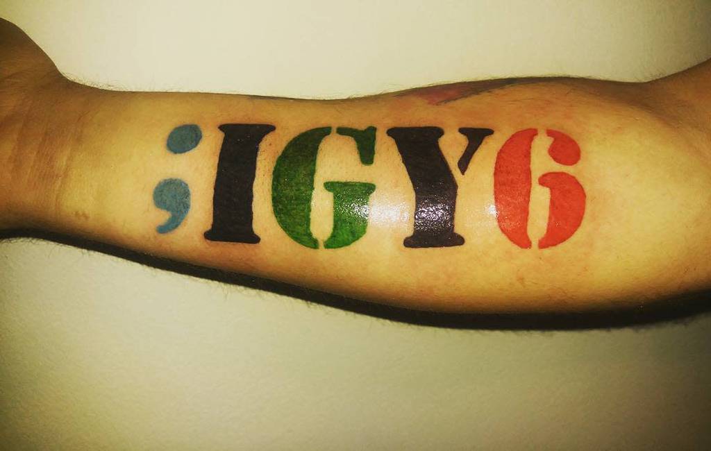 A forearm tattoo with the text ";IGY6" in blue, green, and red ink
