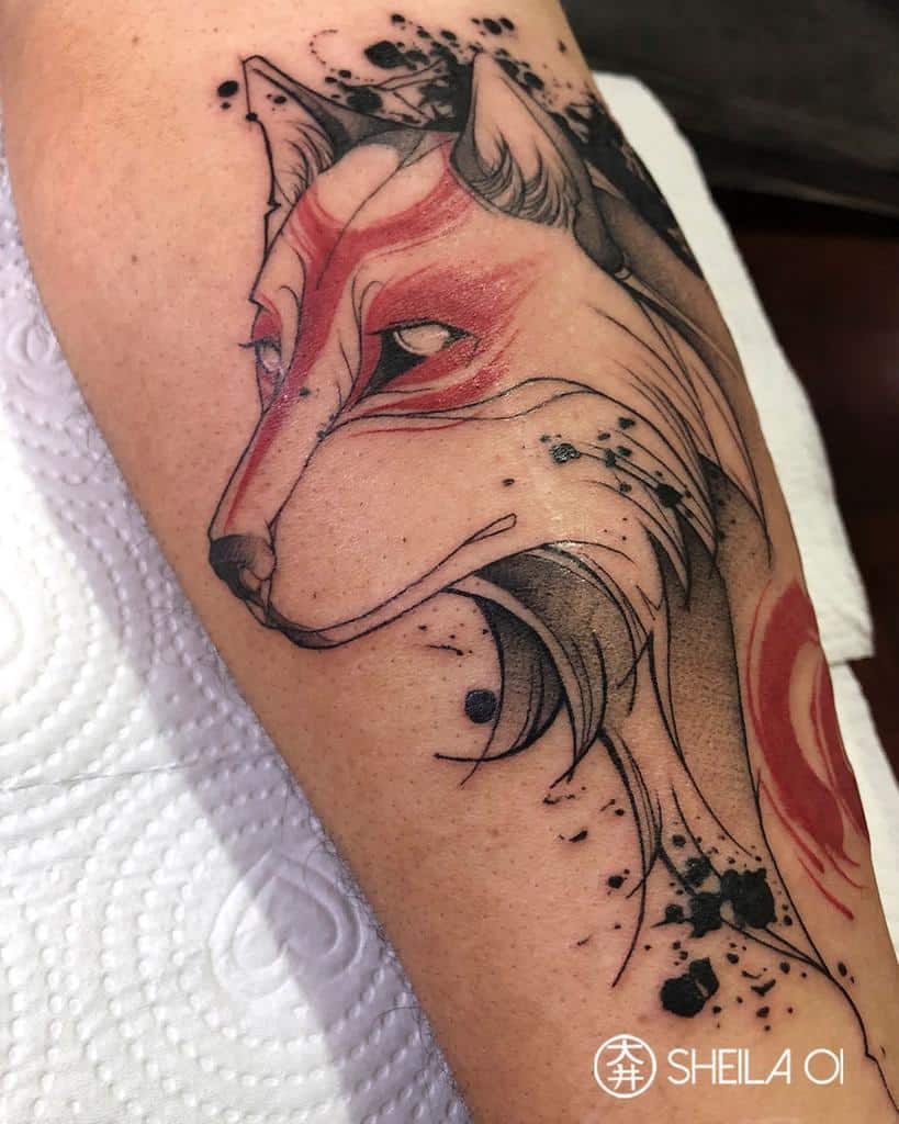 A tattoo of a stylized wolf, reminiscent of Japanese artistry, features striking red and black details on an arm