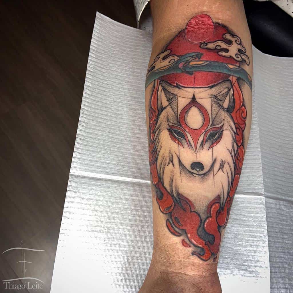 Forearm tattoo of a stylized Japanese wolf wearing red and white headgear, surrounded by clouds and a red sun