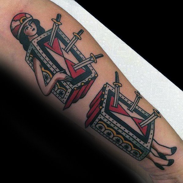 Tattoo of a magician's assistant in a two-piece box illusion pierced with swords