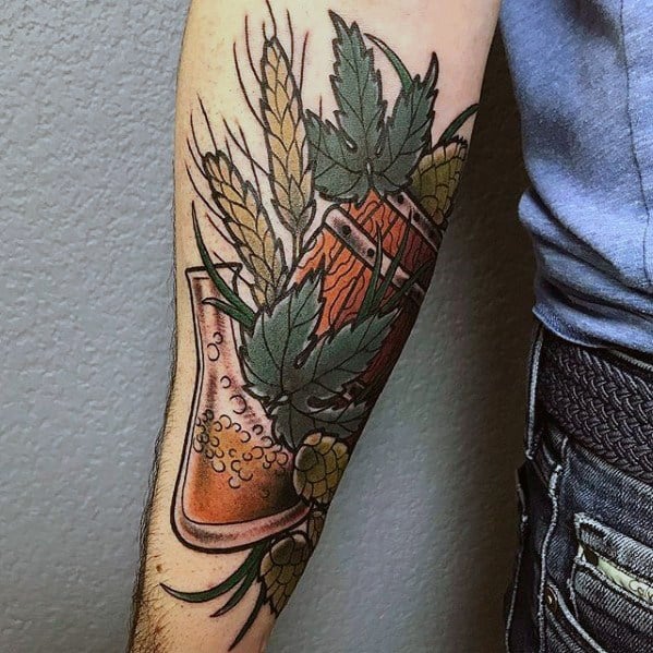 Colorful forearm tattoo featuring a beer mug surrounded by hop cones, barley stalks, and green leaves, blending craft beer symbolism with botanical elements.