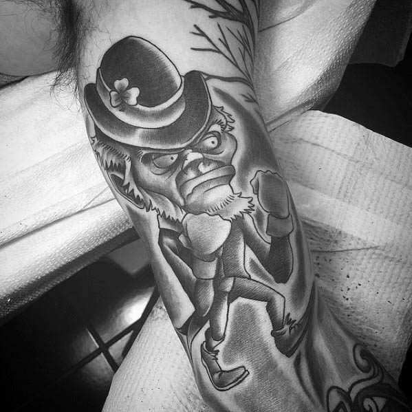 Black and grey tattoo of a fierce leprechaun in a fighting stance, wearing a clover-topped hat and clenched fists ready for battle.