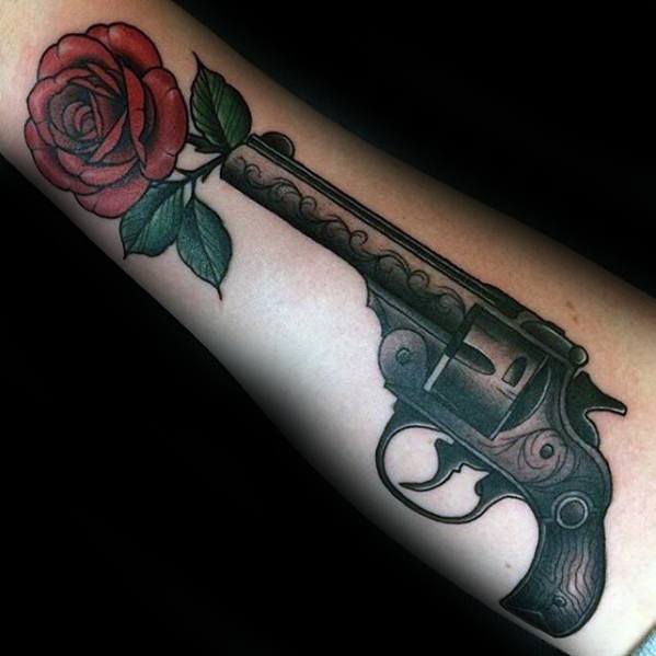 Revolver and rose tattoo on forearm, with the flower blooming from the gun barrel, blending danger and beauty in one design.