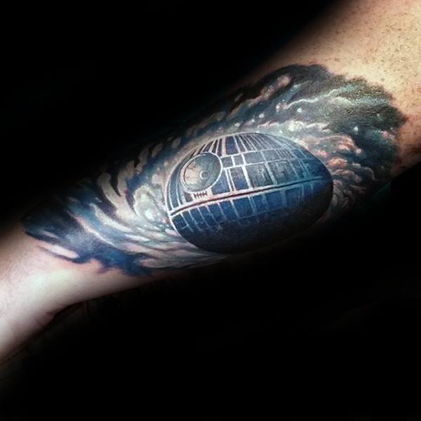 Tattoo of the Death Star with a cosmic background on a person's forearm