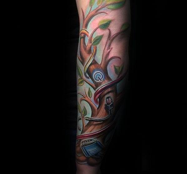 Colorful forearm tattoo featuring a tree with green leaves, tech elements like a power symbol, USB plug, and a computer monitor.