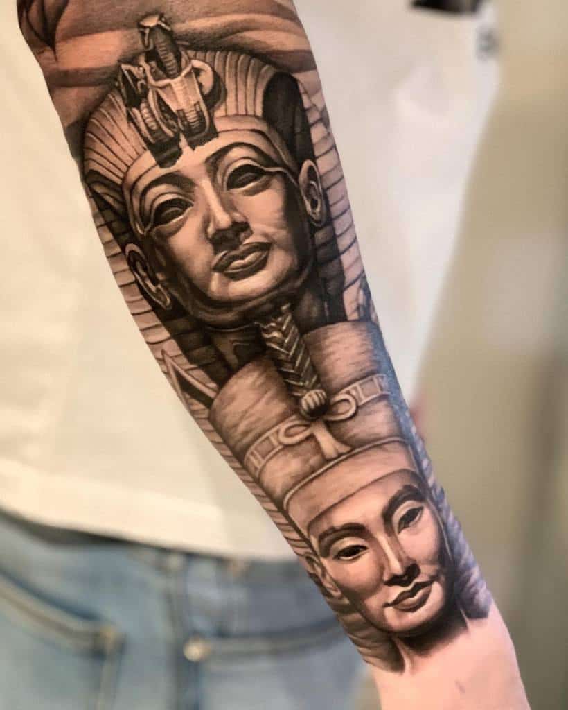 Forearm tattoo with detailed portraits of Egyptian pharaohs, including Nefertiti, in black and gray ink