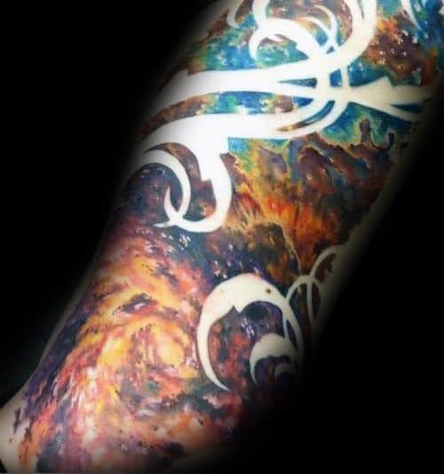 Arm tattoo featuring vivid nebula patterns with white tribal design elements on a dark cosmic background