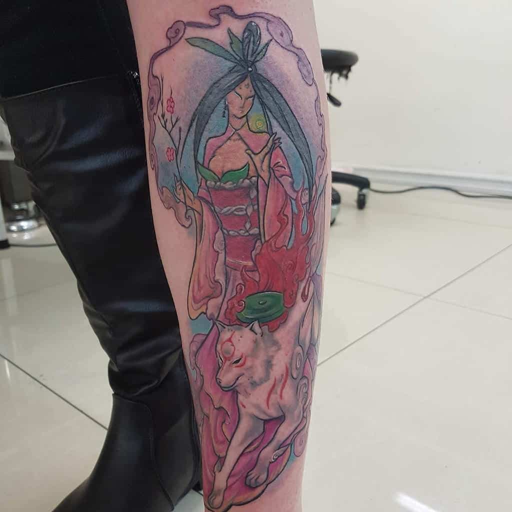 Detailed Okami tattoo on the forearm featuring Amaterasu and a celestial goddess, blending soft pastel hues with flowing divine energy