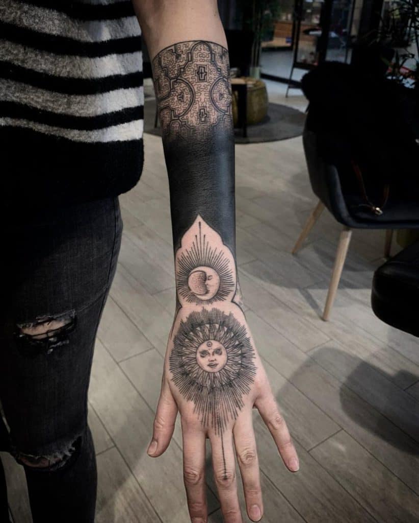 Geometric black ink tattoo featuring interconnected sacred geometry, a sun, a crescent moon, and intricate dotwork for a celestial design.