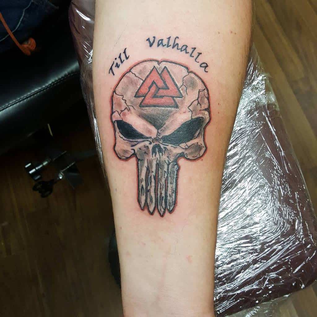 Punisher Skull tattoo on the forearm with a cracked design, featuring the Valknut symbol on the forehead and the phrase "Till Valhalla" for a Norse mythology-inspired tribute