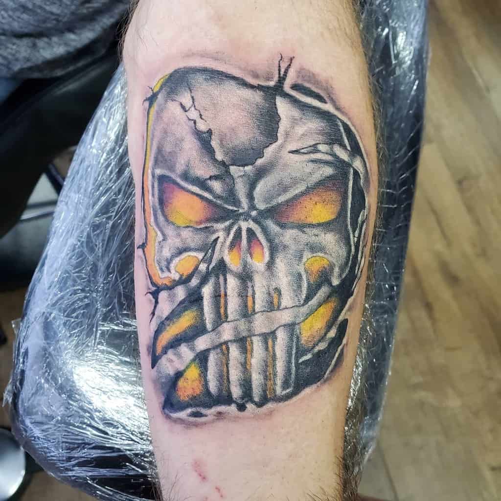 Punisher Skull tattoo with cracked details and fiery orange and yellow eyes, creating an intense and aggressive design with dark shading and depth