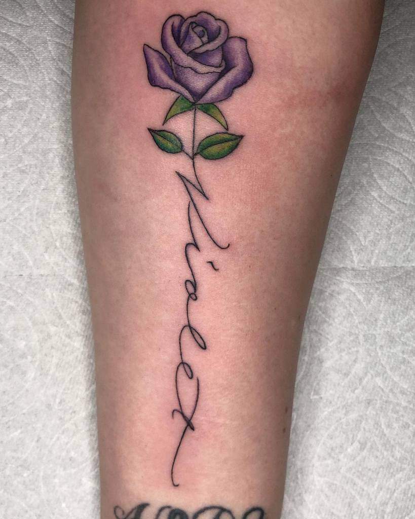 A beautiful tattoo of a purple rose adorns the arm, elegantly complemented by the word "Violet" inscribed in cursive below
