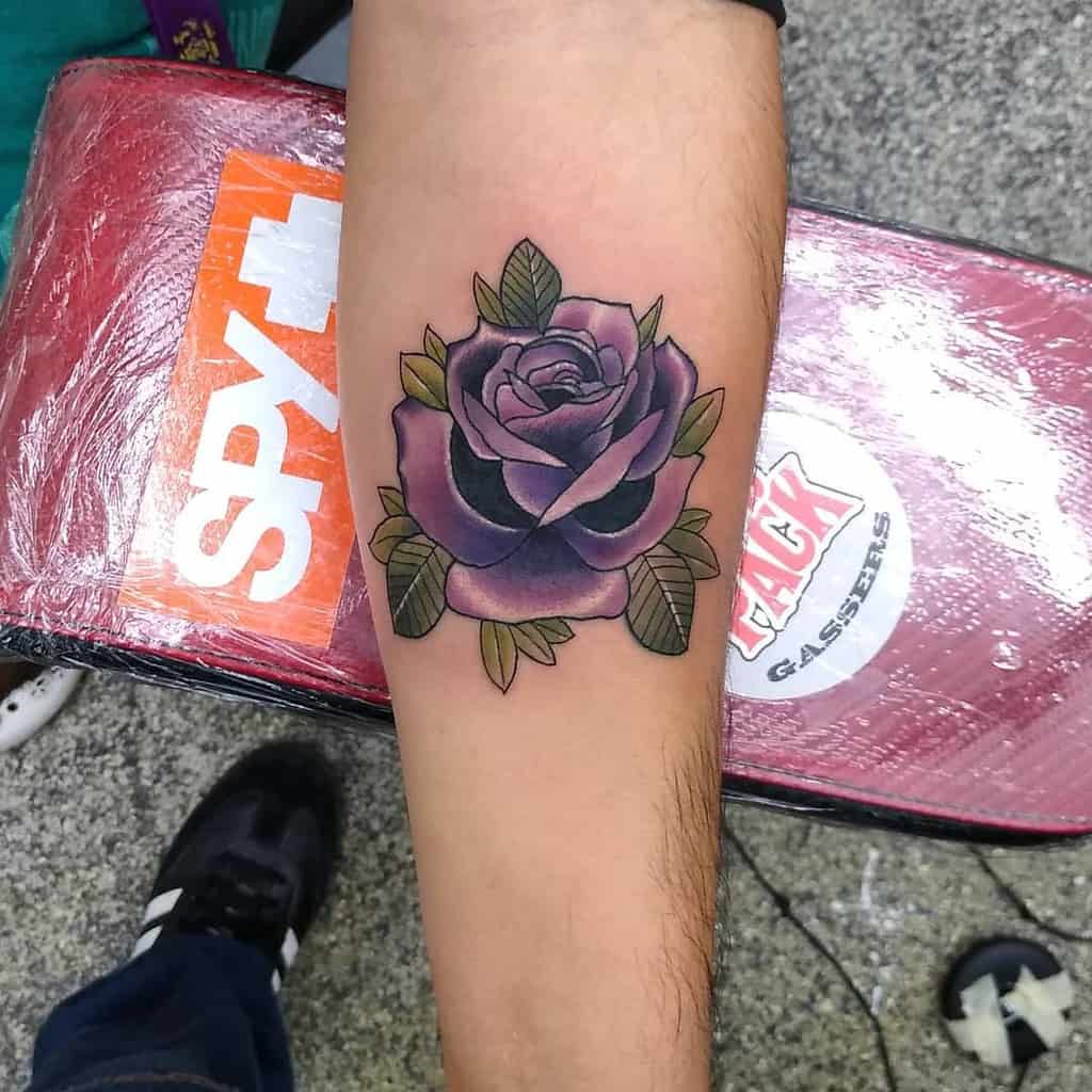 Forearm tattoo featuring a stunning purple rose, its vibrant hue contrasted beautifully with lush green leaves