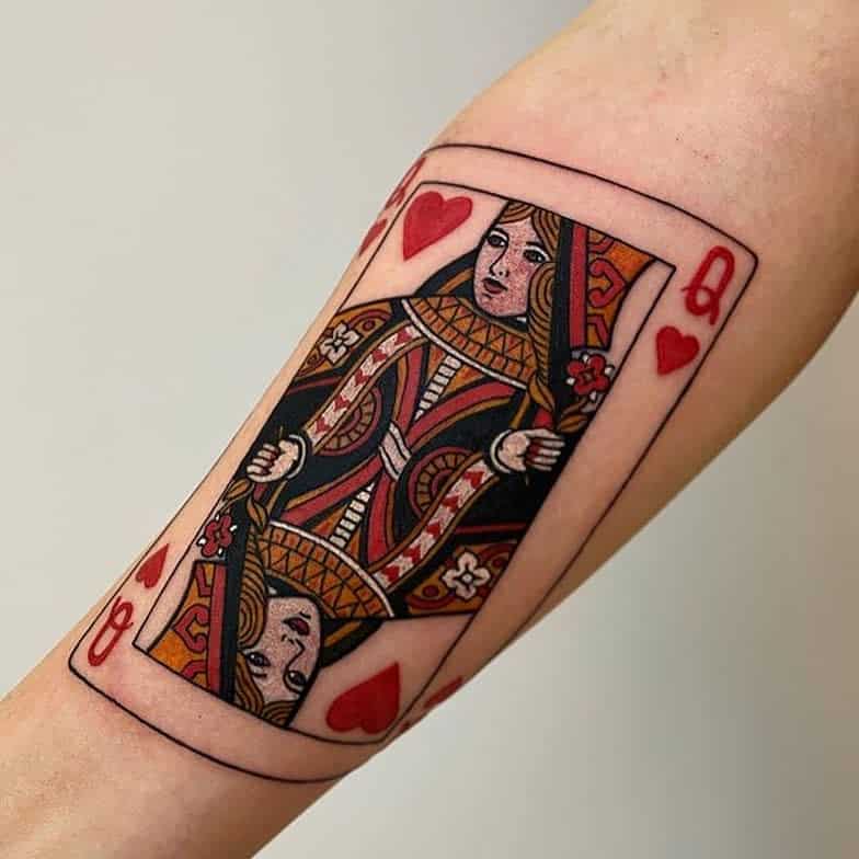 Detailed Queen of Hearts playing card tattoo with bold red and black ink, featuring intricate linework and a classic card design