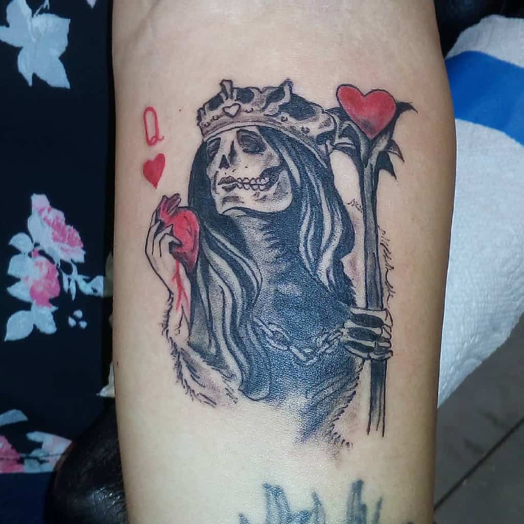 Dark and gothic Queen of Hearts tattoo depicting a skeletal figure holding a bleeding heart and staff, accented by bold black shading
