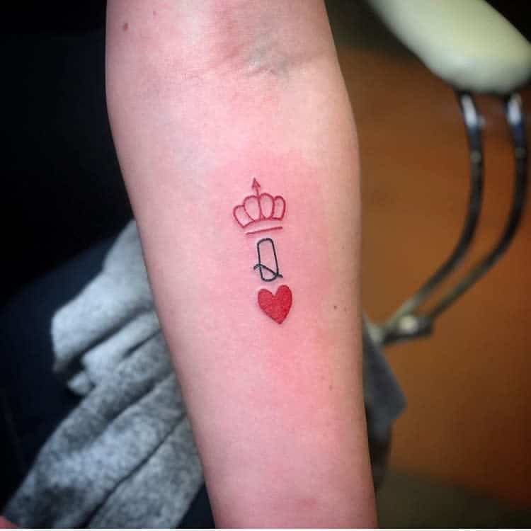Arm tattoo with a crown, letter "Q," and a red heart