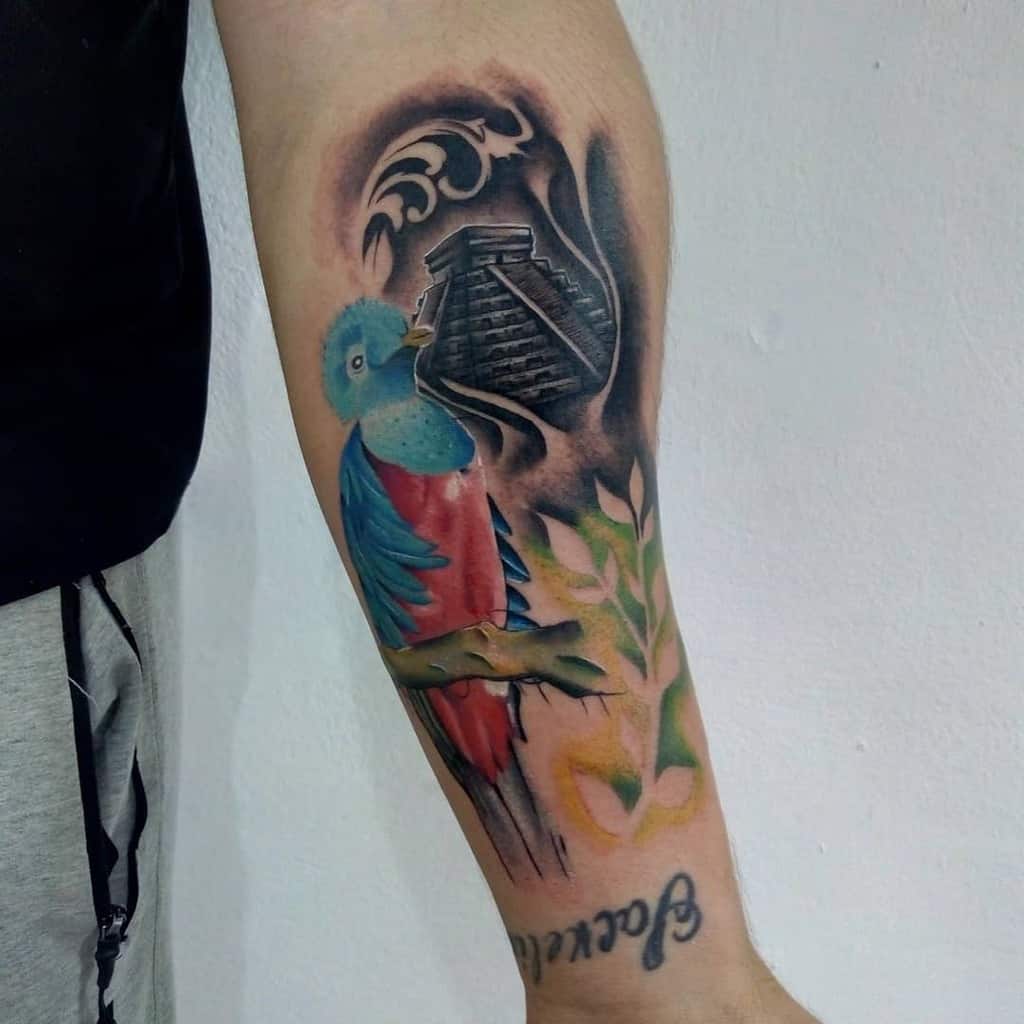 Quetzal and Chichen Itza tattoo on arm, featuring vibrant colors, a pyramid, and foliage