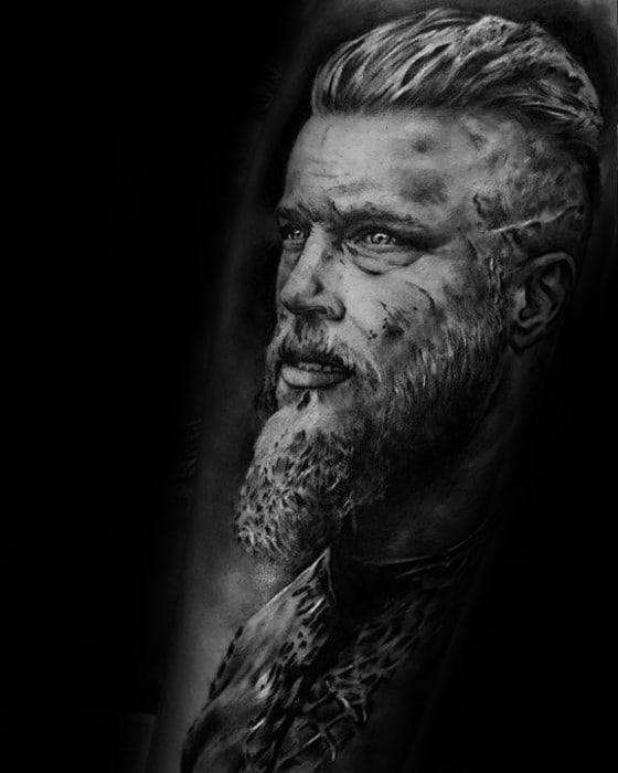 Detailed black-and-white tattoo of a bearded man with a serious expression on his face