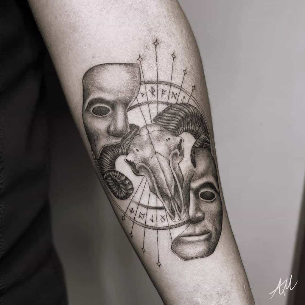 Forearm tattoo featuring a ram skull between two theatrical masks, surrounded by runes and compass-like detailing