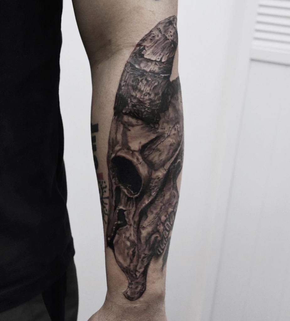 Forearm tattoo of a detailed, realistic ram skull with dark shading
