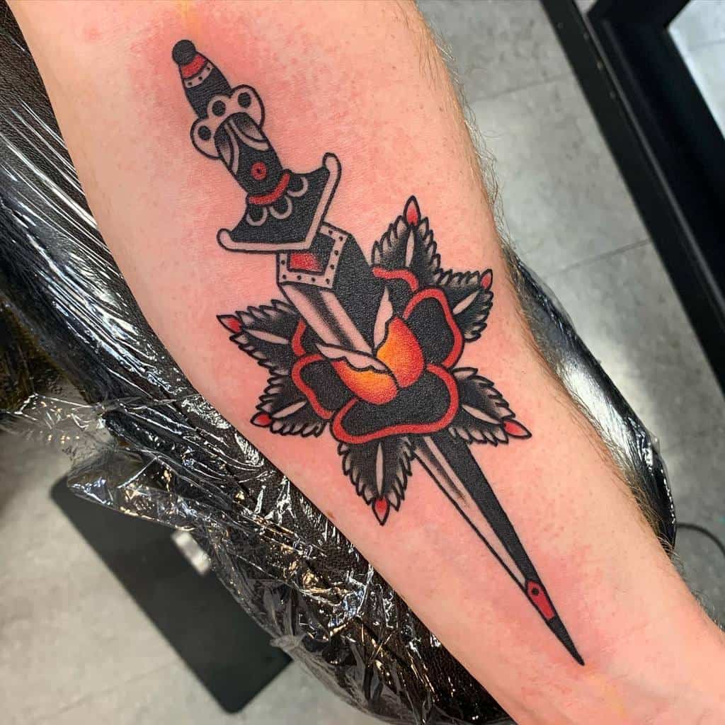 A colorful tattoo of a dagger through a rose on a forearm