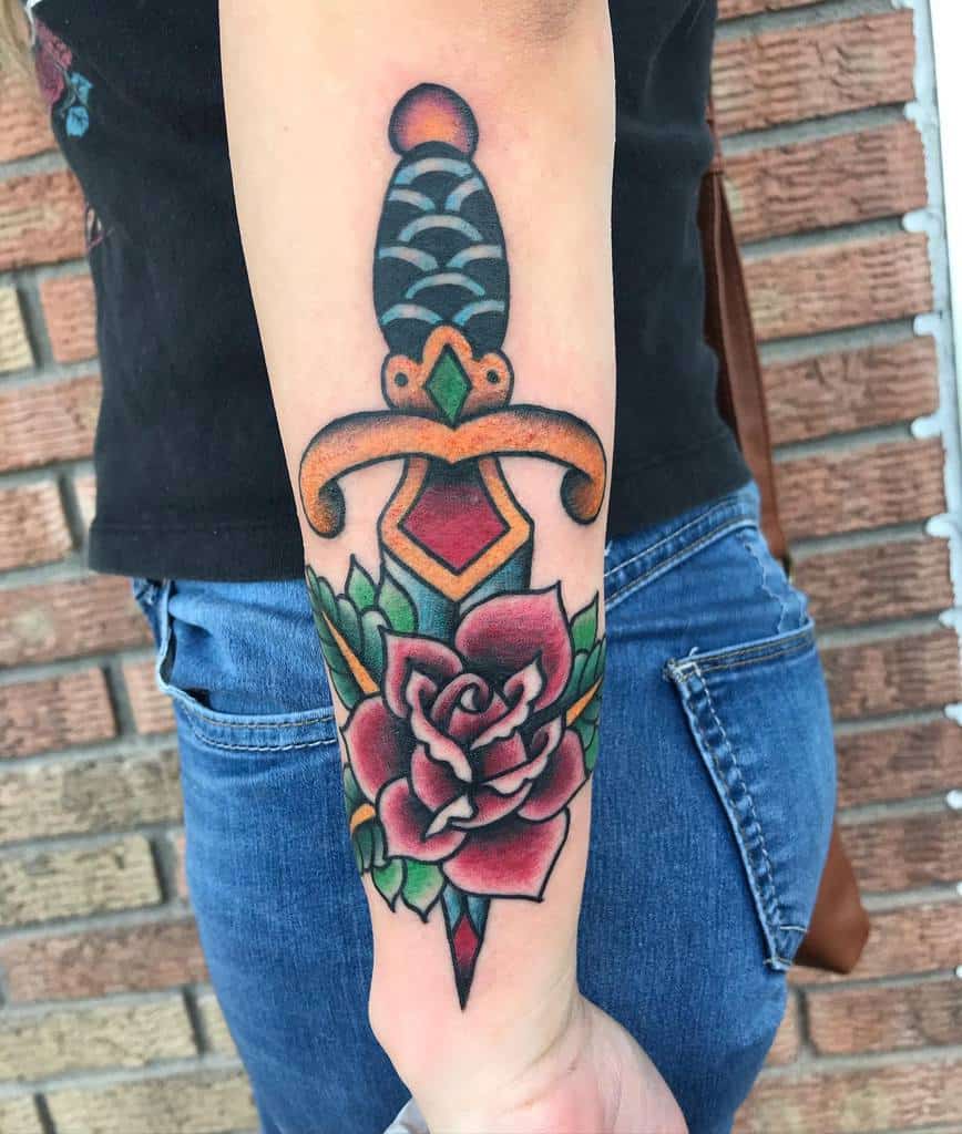 Tattoo of a dagger with a rose on a forearm