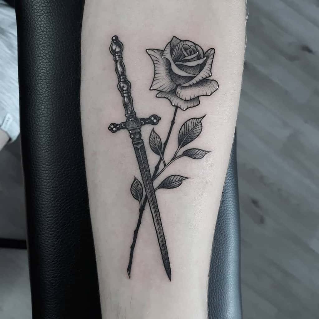 Tattoo of a rose with a dagger on an arm