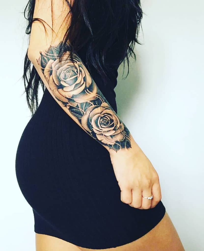 Woman showcasing her rose half sleeve tattoos on her arm