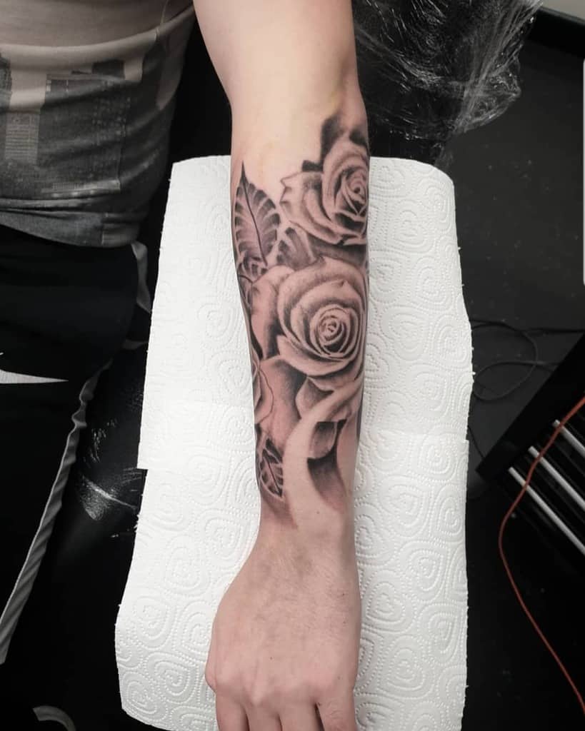 Arm sleeve tattoo of realistic roses and leaves