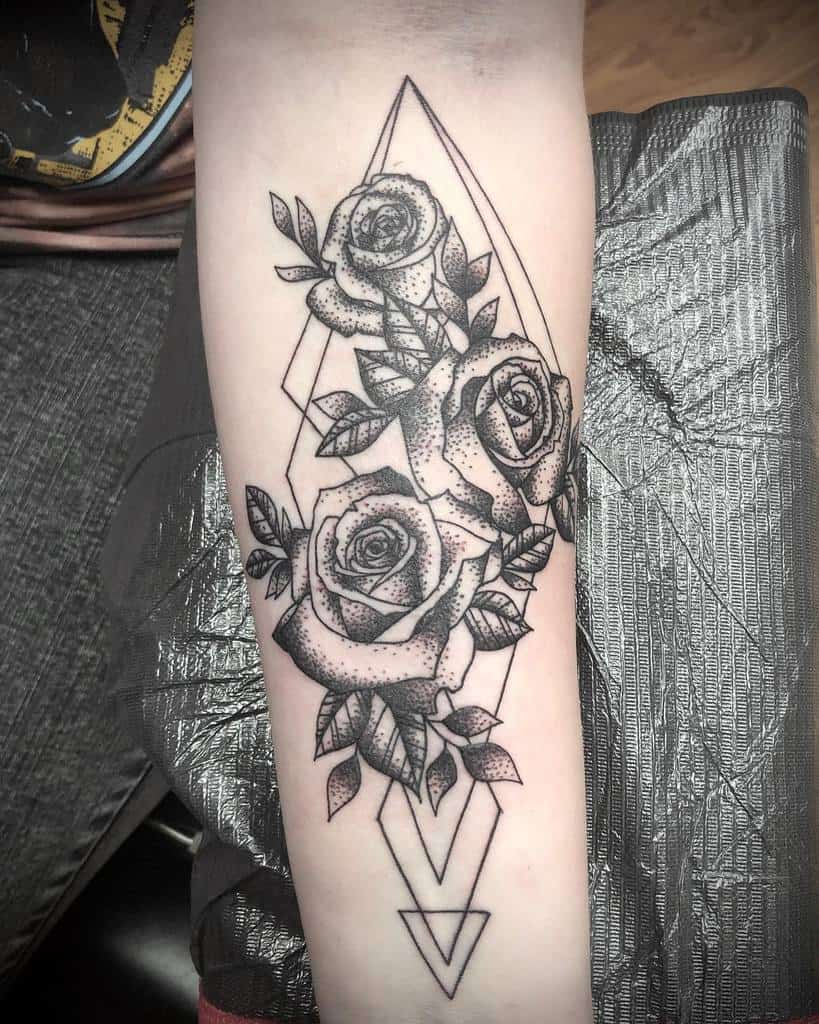 Geometric forearm tattoo featuring detailed roses with dot shading, framed by sharp diamond outlines for a modern artistic style
