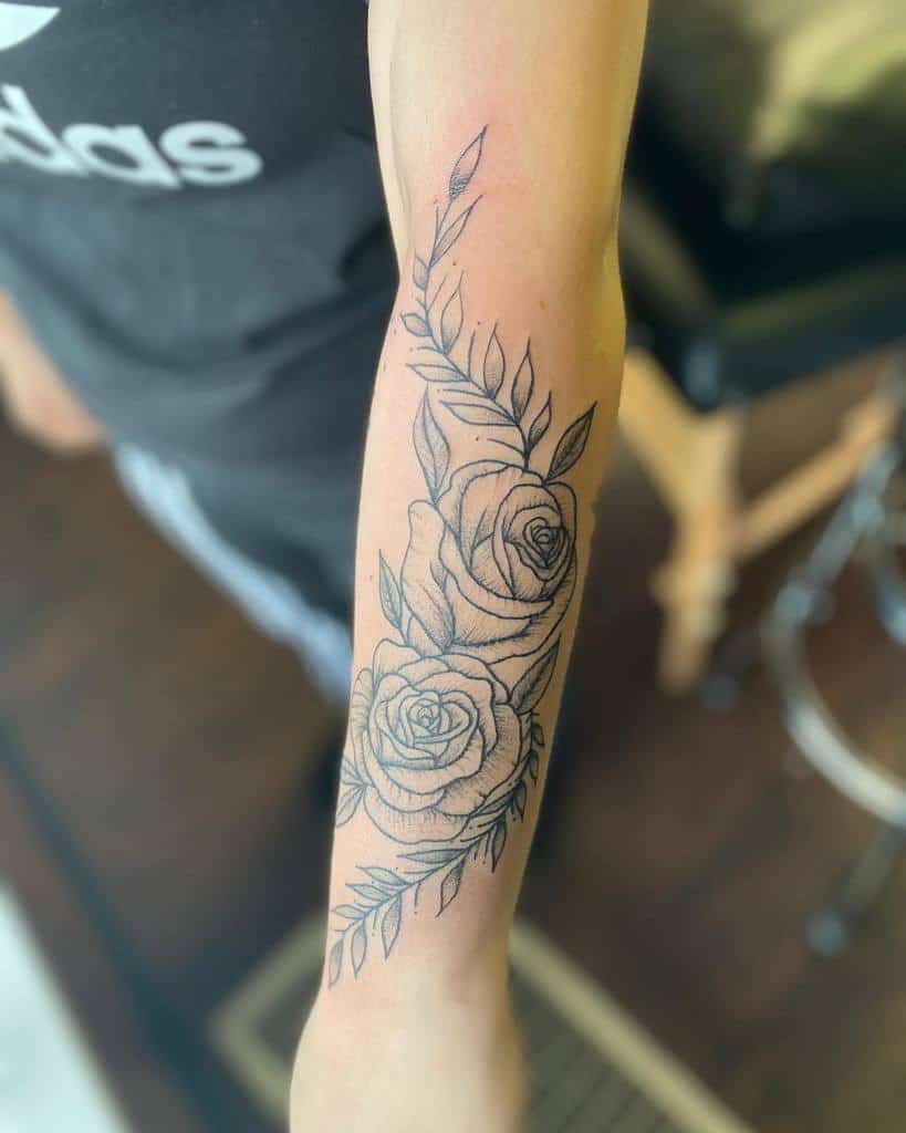 Minimalistic forearm tattoo featuring two detailed roses with delicate leaves and soft linework for a subtle, elegant design