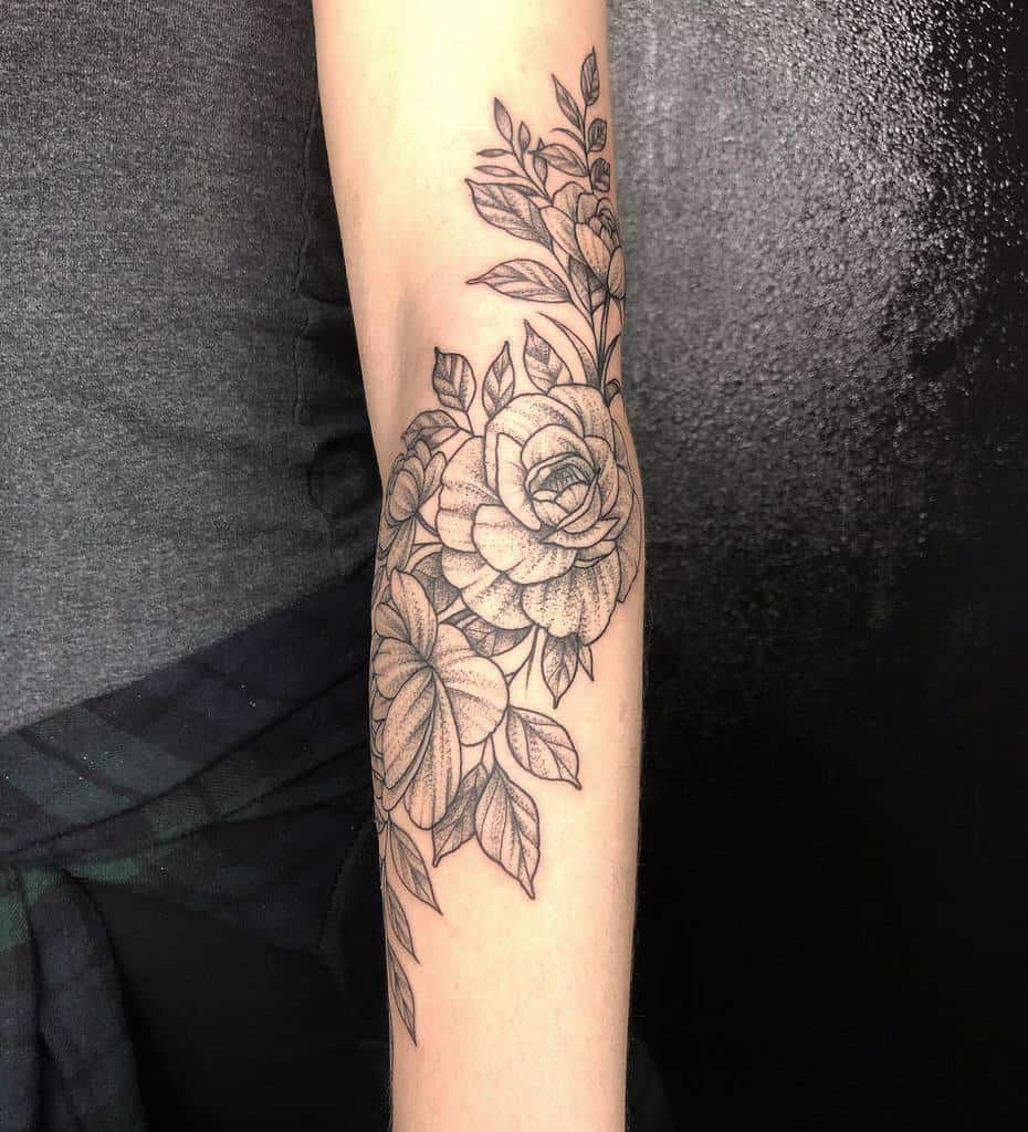Intricate forearm tattoo featuring blooming roses and leafy vines, showcasing detailed linework and a timeless floral design