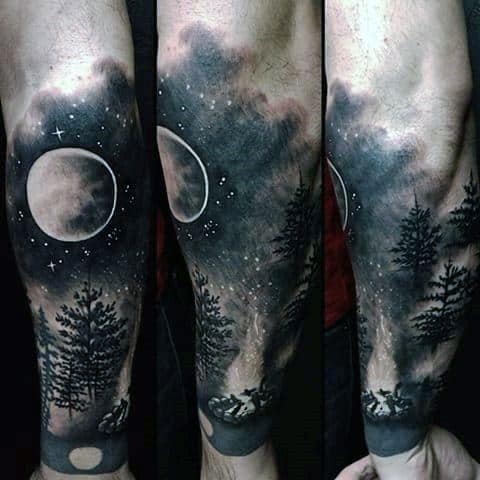 Realistic night sky tattoo sleeve with a glowing moon, starry sky, pine trees, and a small campfire scene near the wrist.