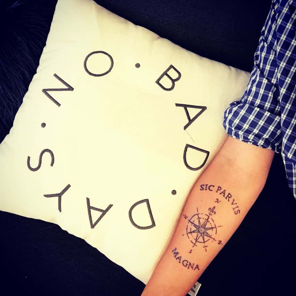 Arm with a compass tattoo reading "SIC PARVIS MAGNA"