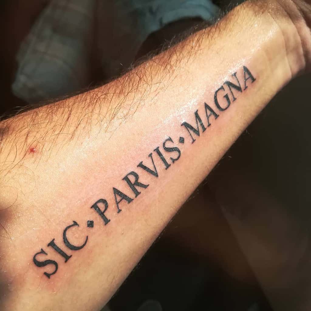 Forearm tattoo with the phrase "SIC PARVIS MAGNA" in black ink