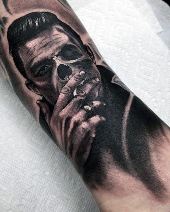 Tattoo of a man with a half-skull face, resembling Johnny Cash, smoking a cigarette on an arm