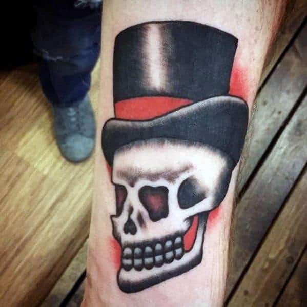 Tattoo of a skull wearing a top hat with a red band on forearm