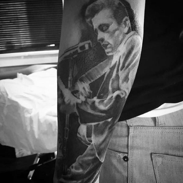 Black and white tattoo of Johnny Cash playing guitar on a person's forearm