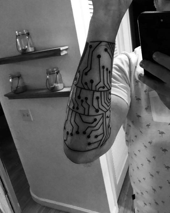 Bold black tattoo of a segmented circuit board design covering the forearm, mimicking the look of layered electronic components.