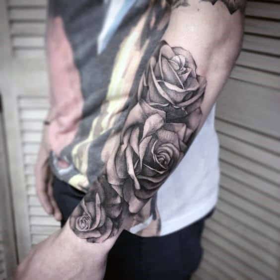 Man with detailed black and gray rose tattoos on his forearm