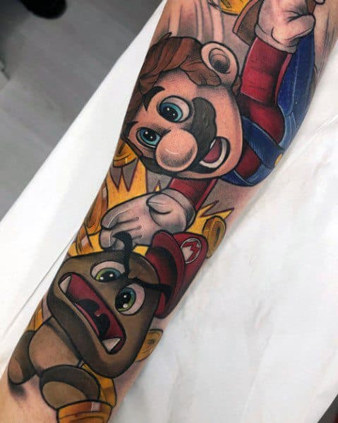Dynamic Mario tattoo on a man's forearm, featuring bold colors and shading as he jumps to stomp a Goomba with coins flying around.