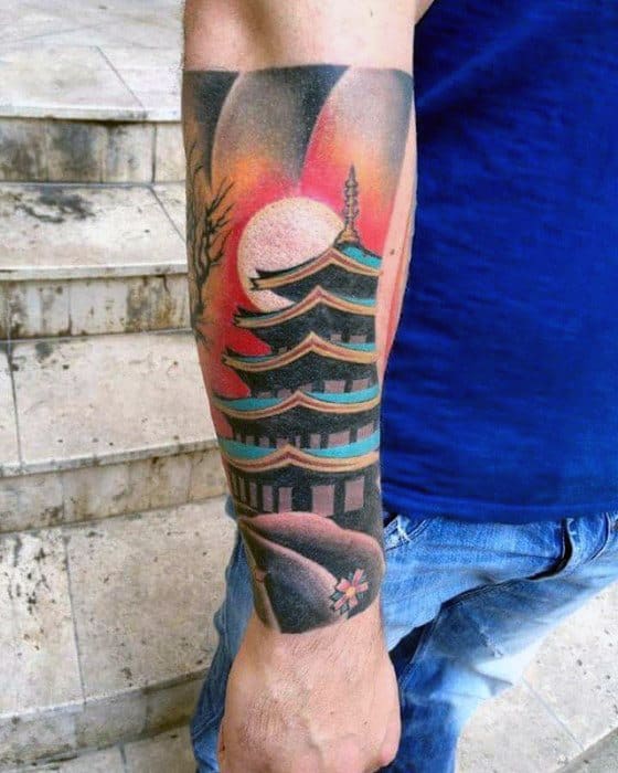 Vibrant forearm tattoo of a Japanese pagoda with a glowing sunset, full moon, and bold red, orange, and teal tones.
