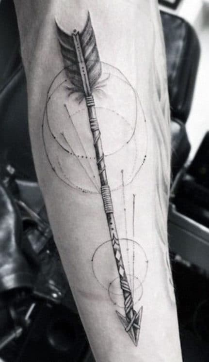 Black and white tattoo of an arrow with geometric circles on a person's forearm