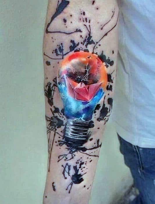 Tattoo of a light bulb with colorful artwork and abstract splashes on a person’s forearm