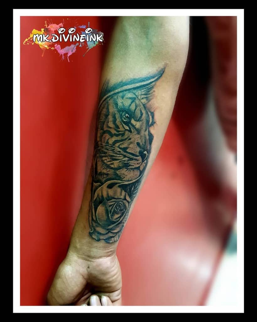 Forearm tattoo seamlessly combines a majestic tiger with a blooming rose