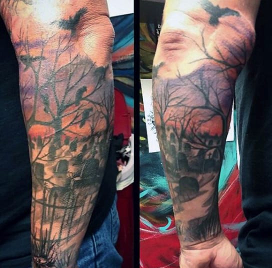 Forearm tattoo of a haunting graveyard scene with trees, gravestones, and ravens in flight