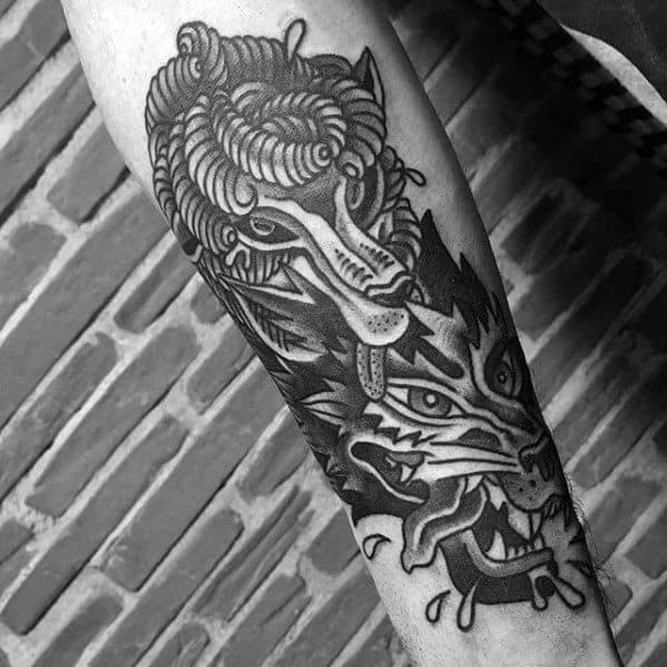 Arm tattoo featuring a stylized ram's head above a fierce wolf's head in black ink