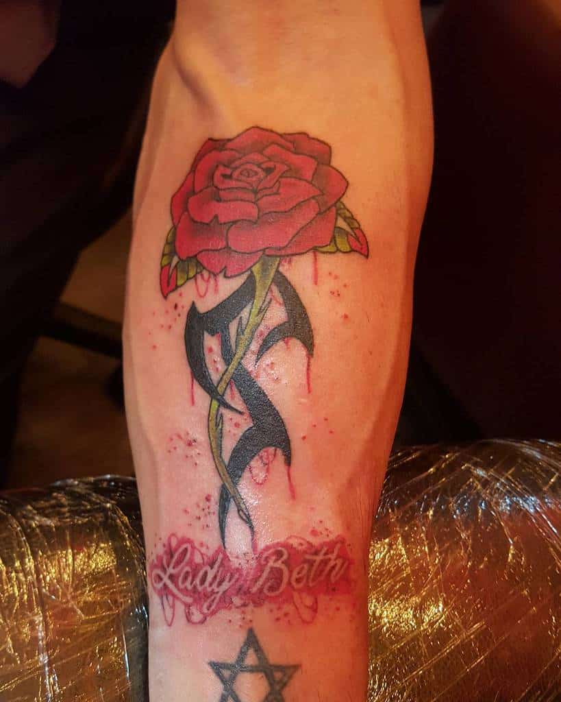 Tattoo of a tribal-themed red rose with "Lady Beth" text and a Star of David on the arm